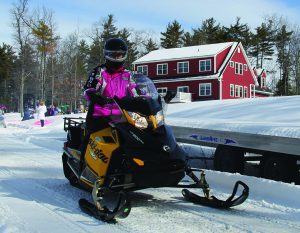 Snowmobile rider dressed in pink drives by